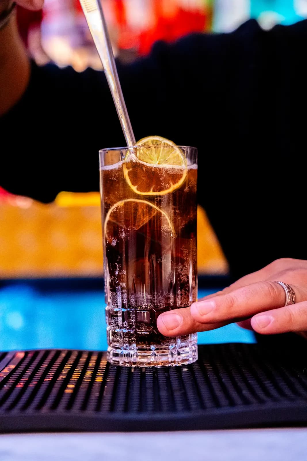 Barkeeper serviert einen Longdrink mit getrockneter Solenara-Zitronenscheibe